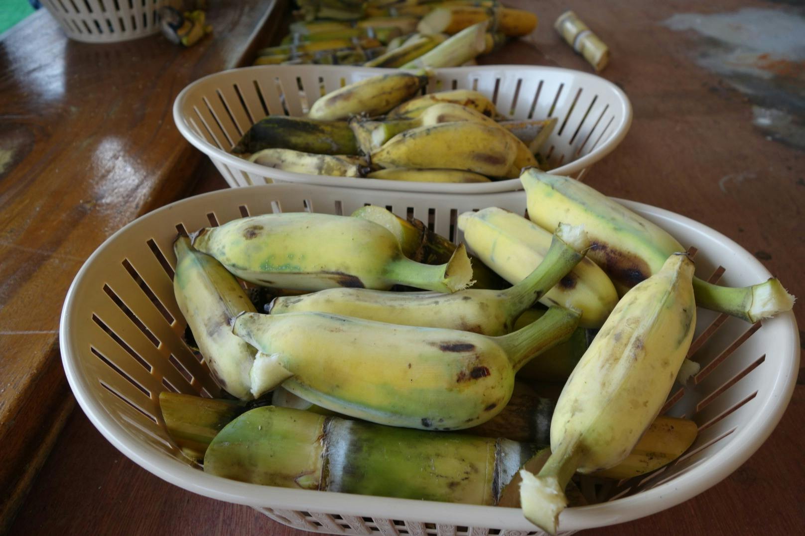 在木质表面放置两个装满去皮香蕉的篮子。