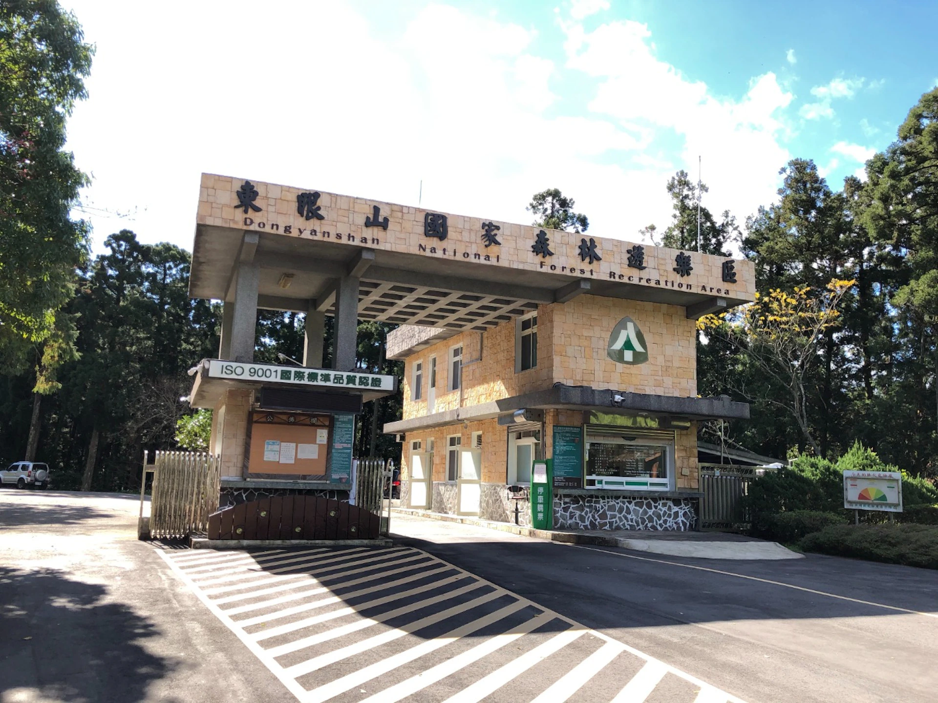Entrance gate to Dongyanshan National Forest Recreation Area with a building, signboards, and surrounding greenery.