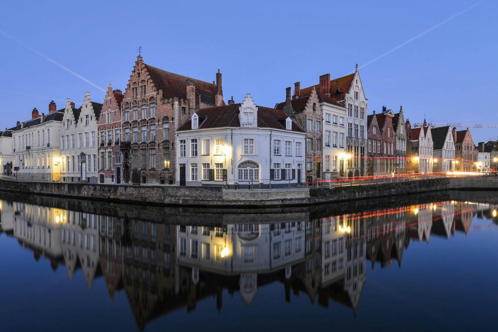 运河边的欧洲建筑，立面华丽，屋顶为山墙，倒映在暮色天空下的宁静水面上。