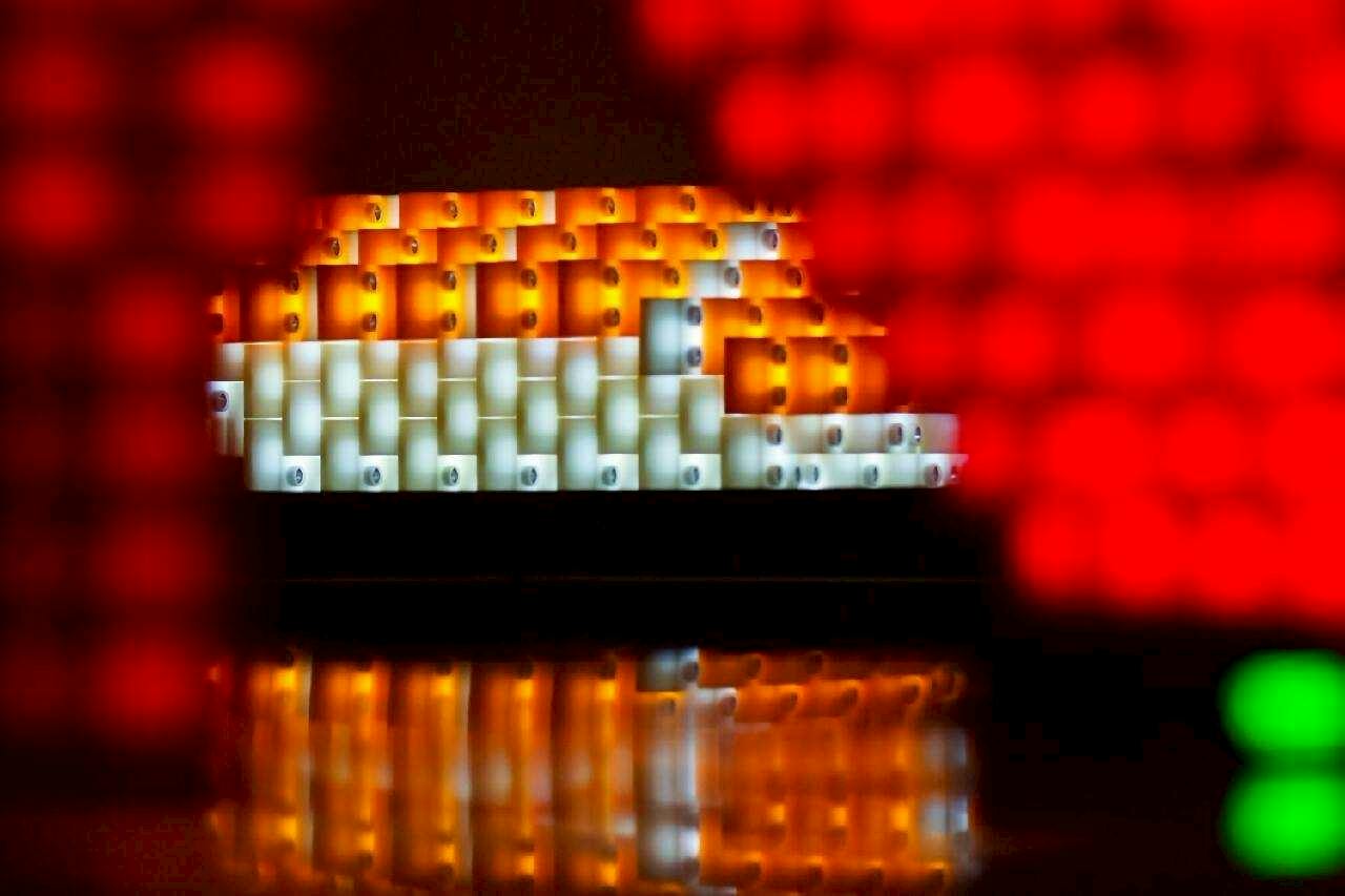 A structure made of illuminated orange and white blocks, blurred red elements in the foreground.