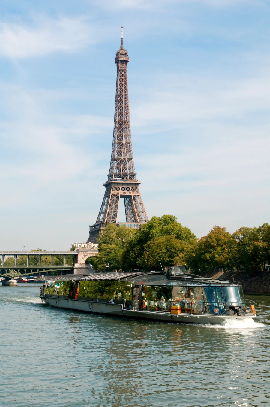 Een rondvaartboot op de Seine met de Eiffeltoren en bomen op de achtergrond