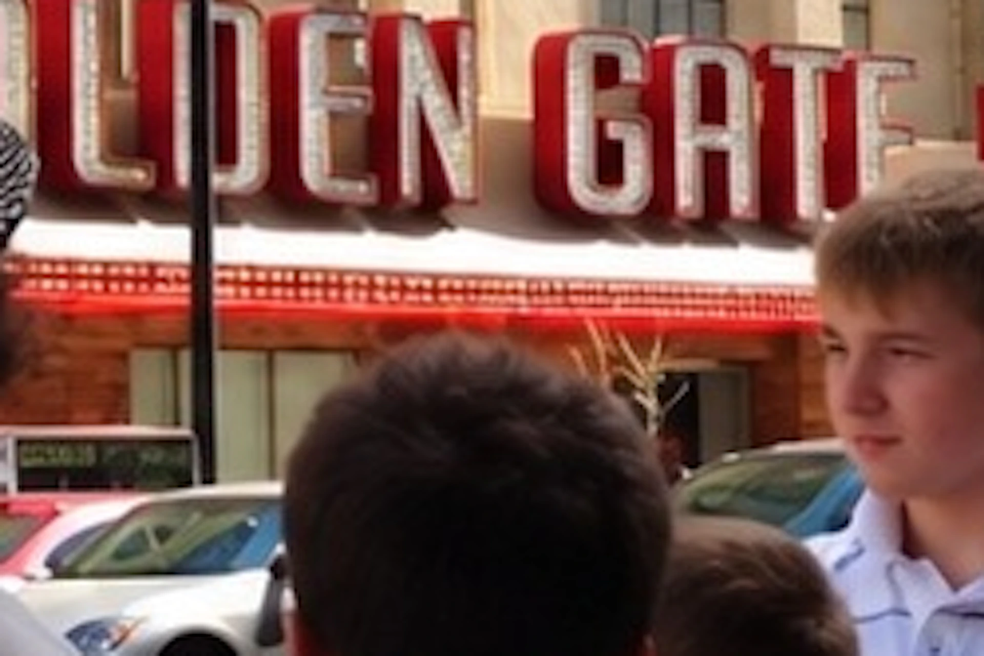 A group of people standing on a street near a building with a sign reading 'Golden Gate Casino,' under a clear sky.
