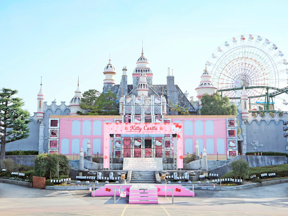 A pink-themed castle labeled "Kitty Castle" with a ferris wheel in the background under a clear blue sky.
