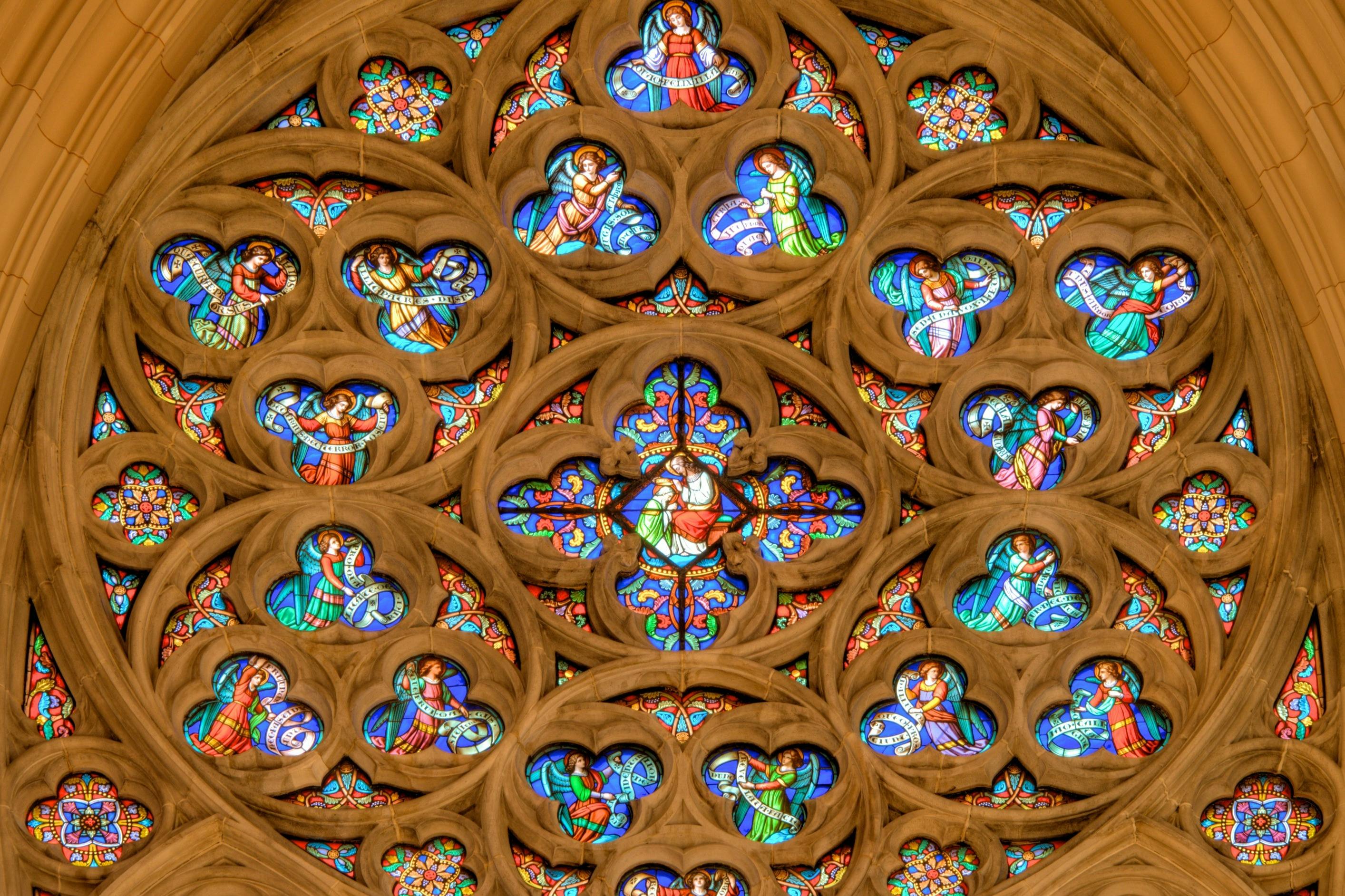 A close-up view of a cathedral's rose window with intricate stained glass and ornate stone tracery.