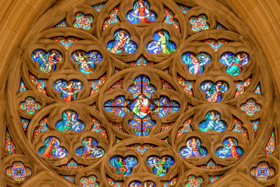 A close-up view of a cathedral's rose window with intricate stained glass and ornate stone tracery.