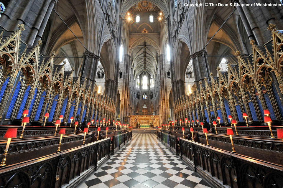 Ornate cathedral interior with high vaulted ceilings, checkered tile floor, and rows of candlelit pews leading to an altar.