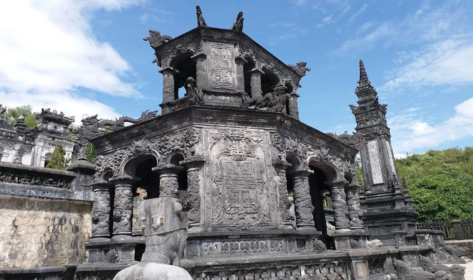 An intricately carved stone structure with decorative details and columns under a blue sky.