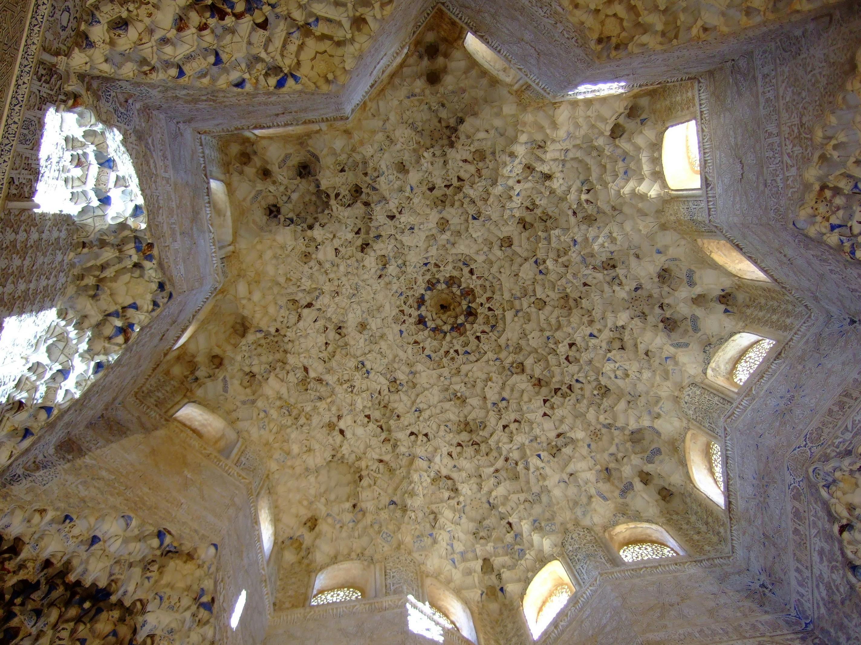 Ornate ceiling with intricate, star-shaped patterns and small windows, surrounded by detailed stone or plasterwork.
