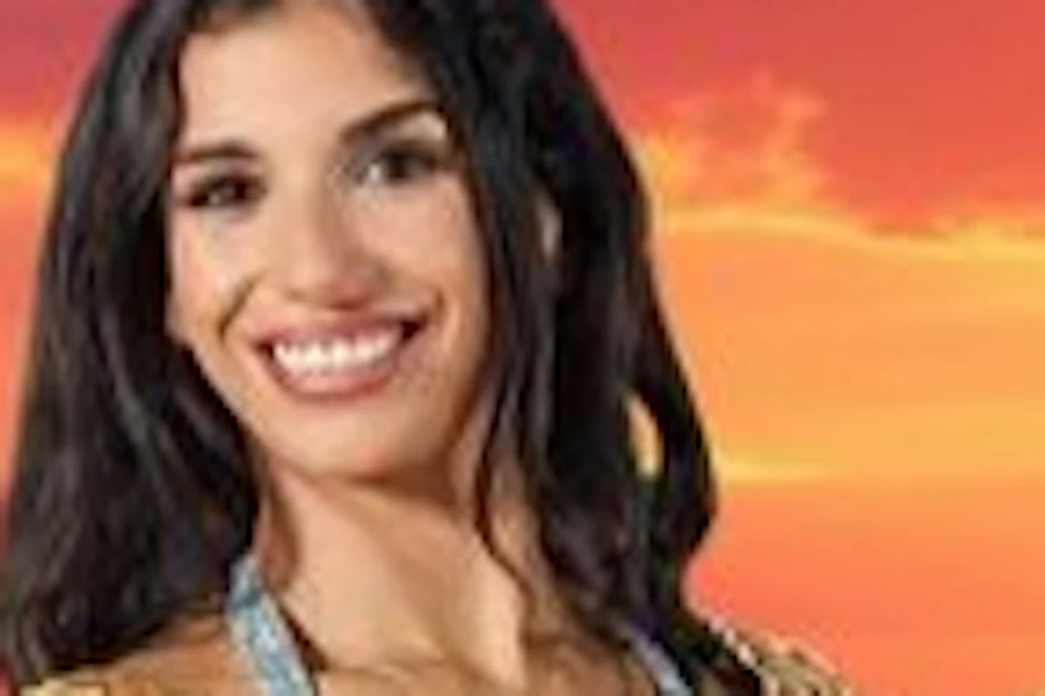 Three women dressed in ornate belly dance costumes perform against a backdrop of a vibrant sunset over desert dunes.