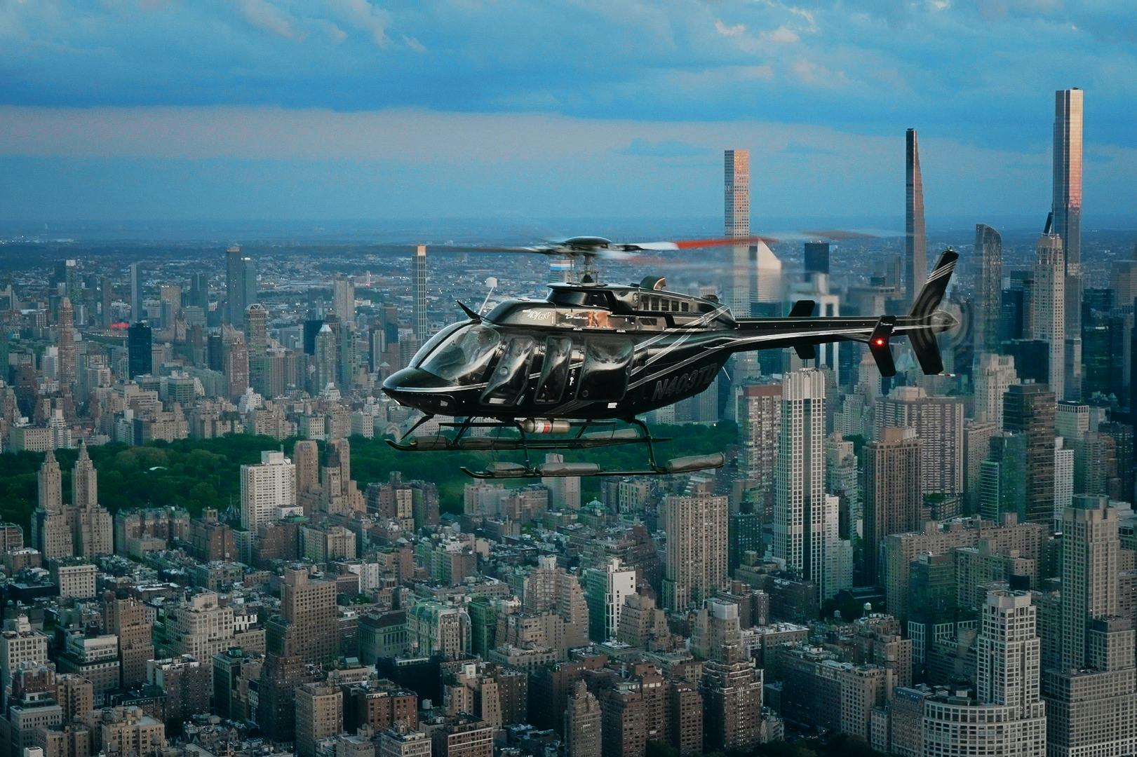 수많은 고층 건물과 그 아래에 커다란 공원이 있는 도시 풍경 위를 날고 있는 검은 헬리콥터입니다.