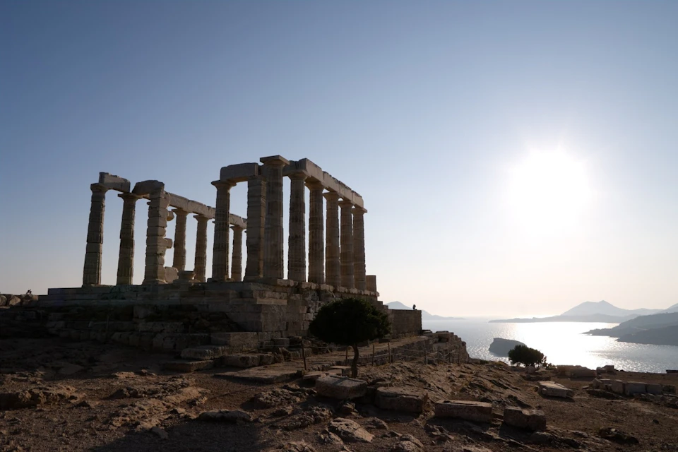 Temple of Poseidon silhouetted at sunset over the Aegean
The ancient ruins glow as the sun sets over cliffs and islands.