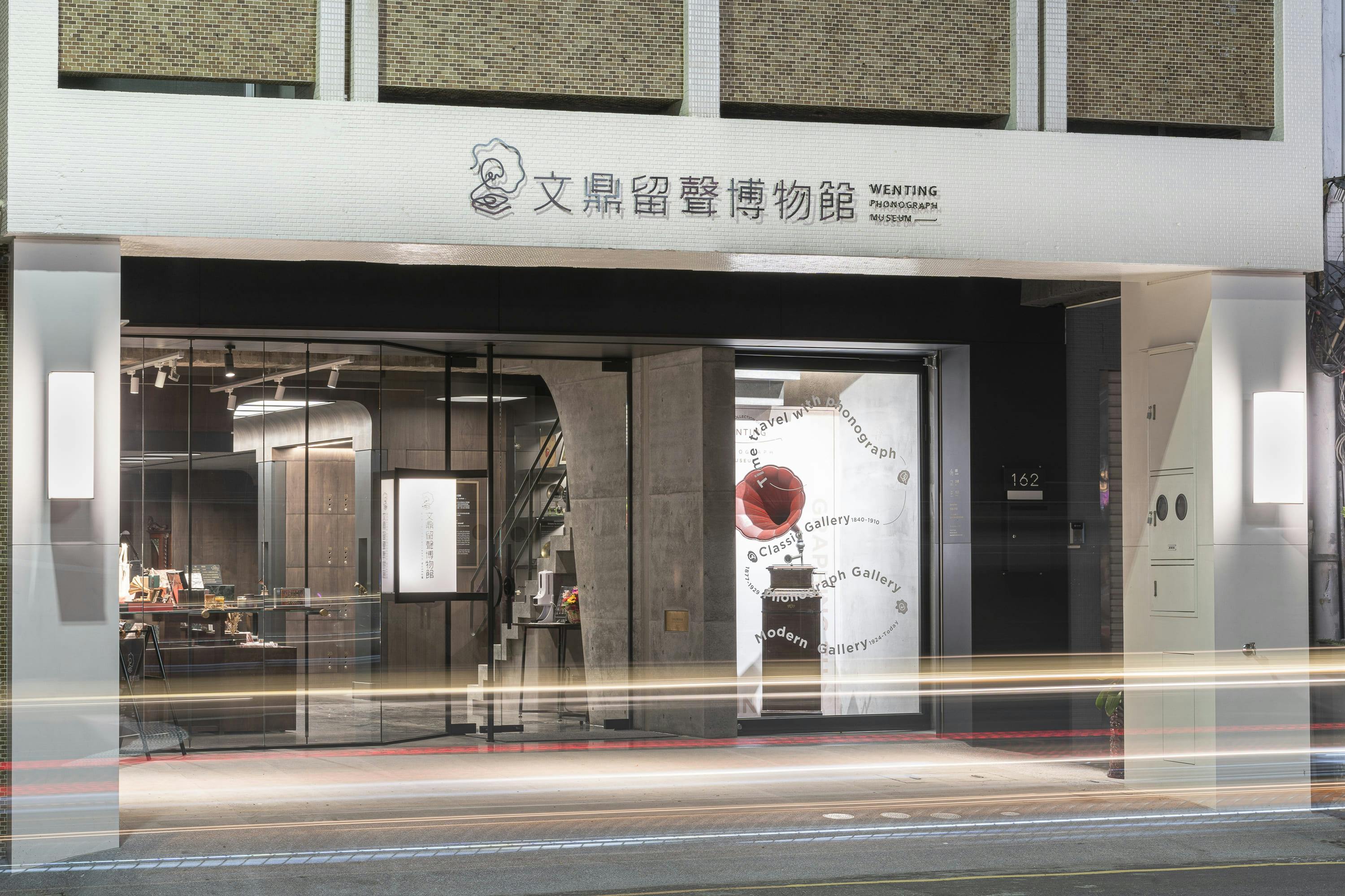 A modern storefront with glass doors and a sign above in Chinese and English, reading "Wenting Photograph Museum."