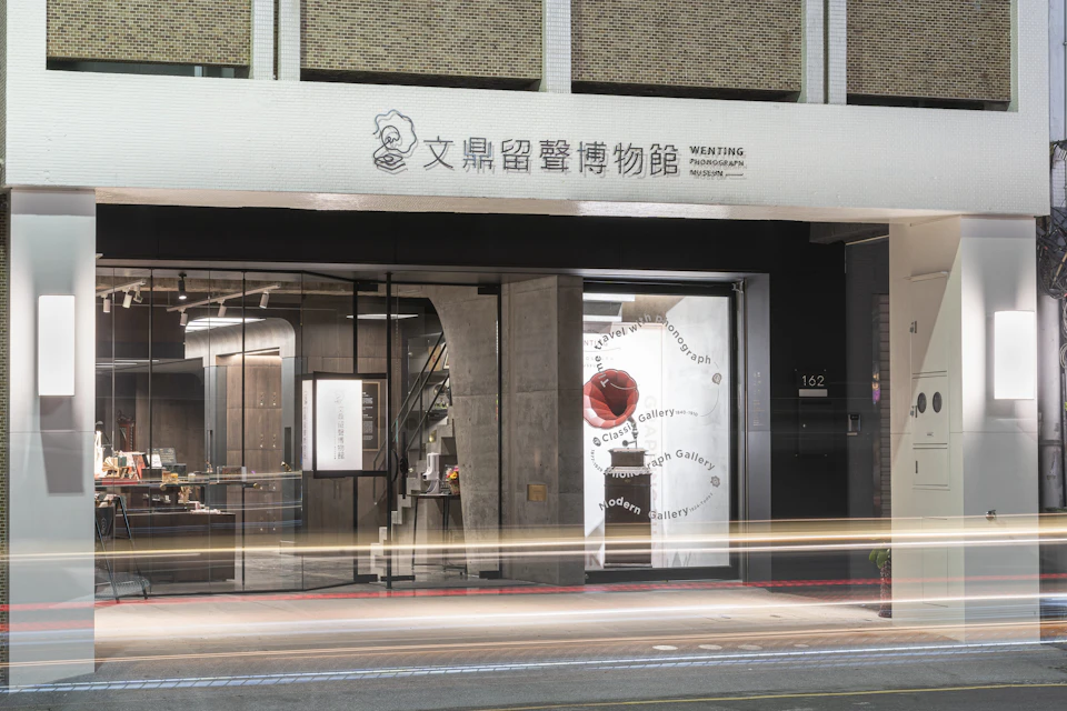 A modern storefront with glass doors and a sign above in Chinese and English, reading "Wenting Photograph Museum."