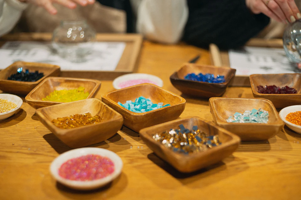 Wooden trays filled with colorful mosaic stones on a workshop table.