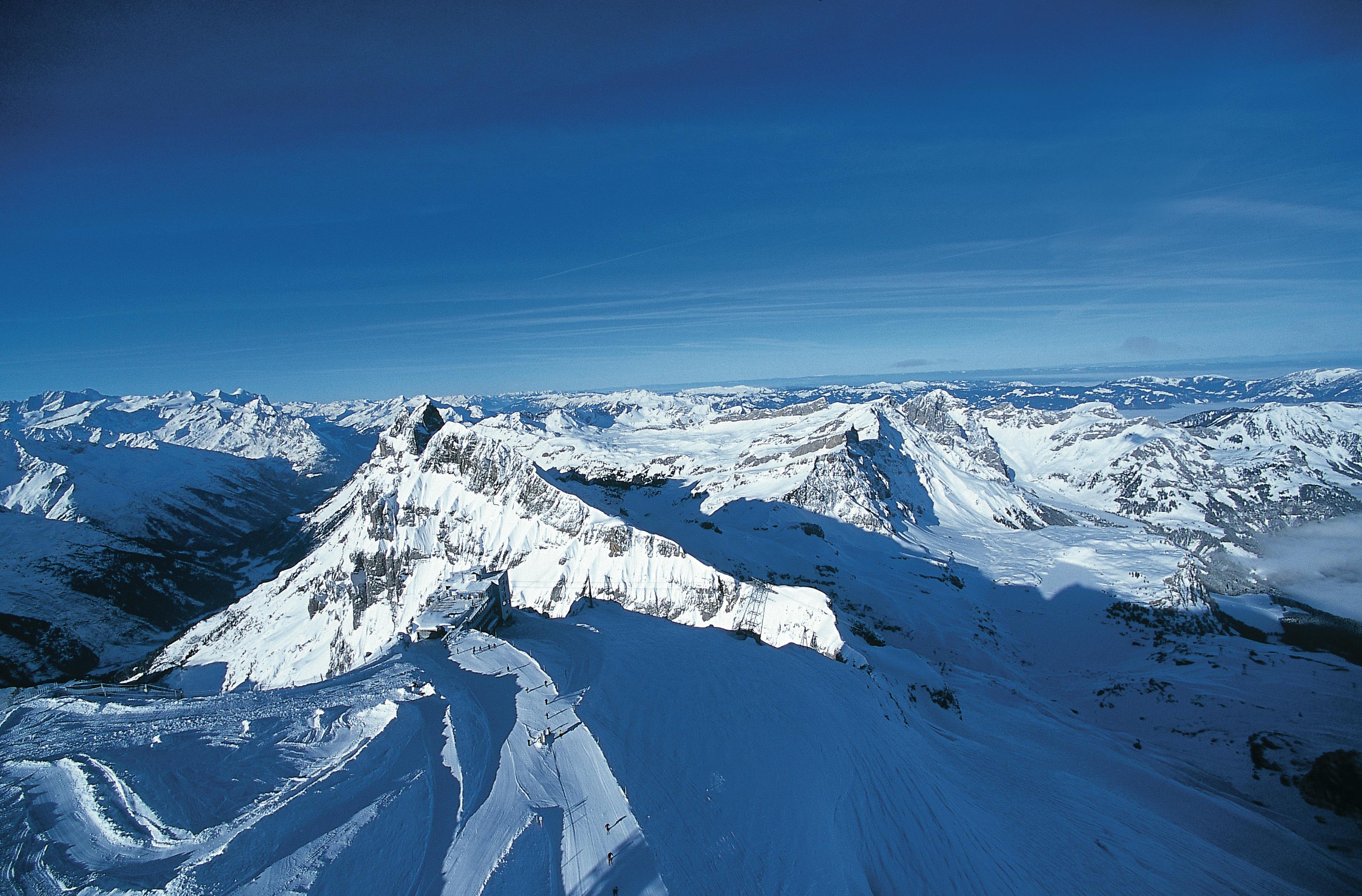 Χιονισμένες βουνοκορφές που εκτείνονται σε απόσταση κάτω από έναν καταγάλανο ουρανό.