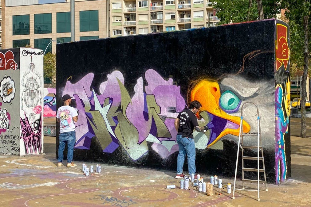 Pouliční umělec v procesu tvorby své práce na městské zdi.