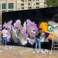 Уличный художник в процессе создания своей работы на городской стене.