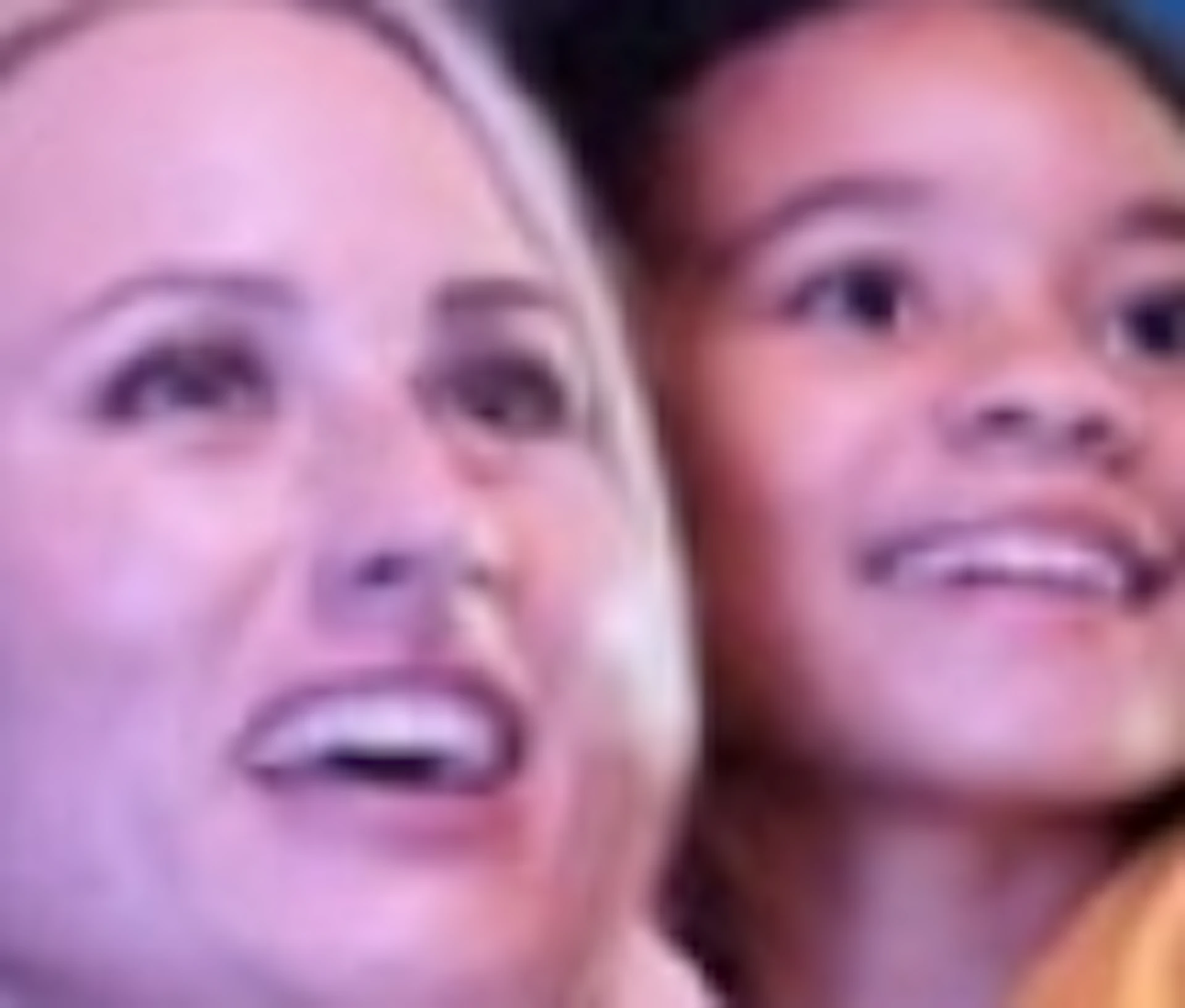 A family of four smiles and points at sea life while inside an aquarium tunnel, surrounded by fish and a sea turtle overhead.
