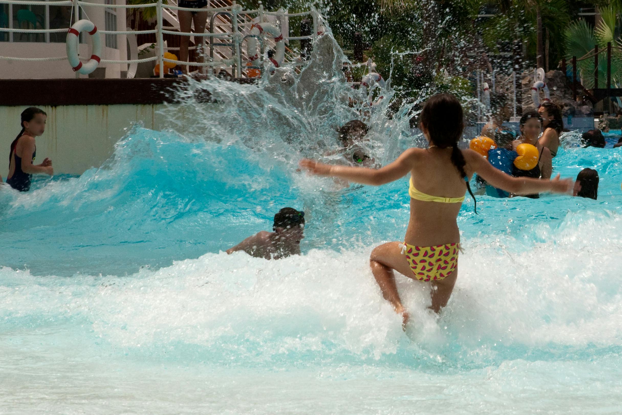 Children playing and splashing in a wave pool on a sunny day.