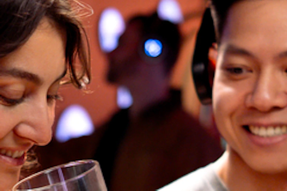 Two people wearing headphones explore a sensory exhibit, holding small containers and interacting with displayed items.