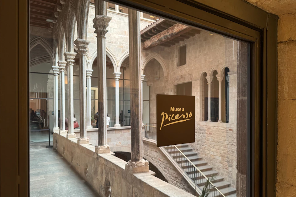 The glass door of the museum reflects the stunning medieval courtyard, with Gothic-style arches and stone walls.