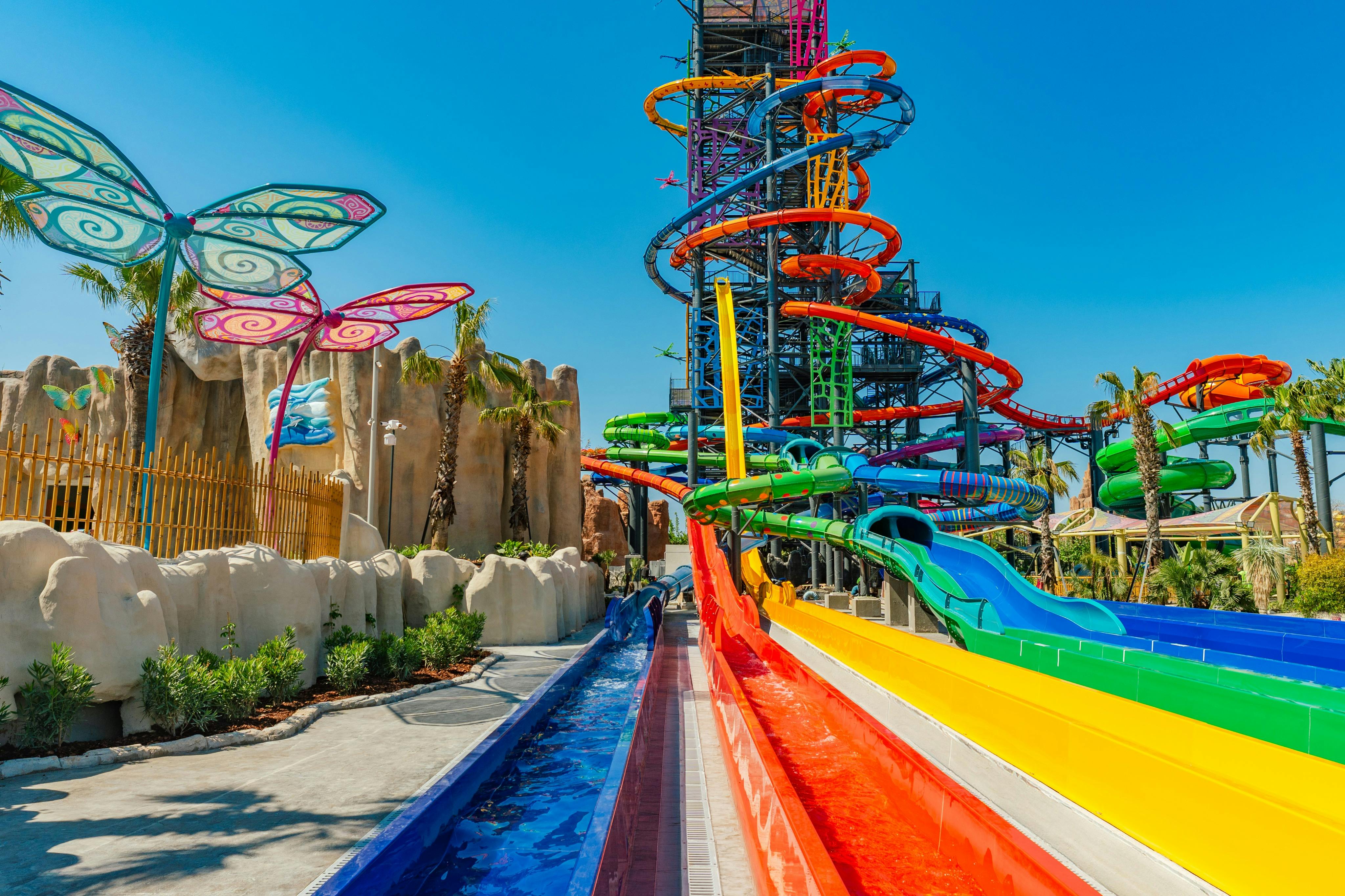 Un parc aquatique dynamique avec des toboggans colorés, un ciel bleu clair et un thème ludique et tropical.