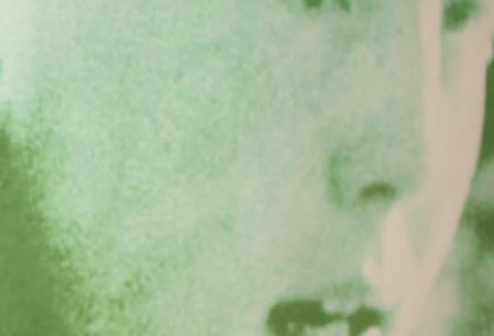 Close-up of a green-tinted photograph of a person in winter attire, with an antique ice skate and a small label in the foreground.
