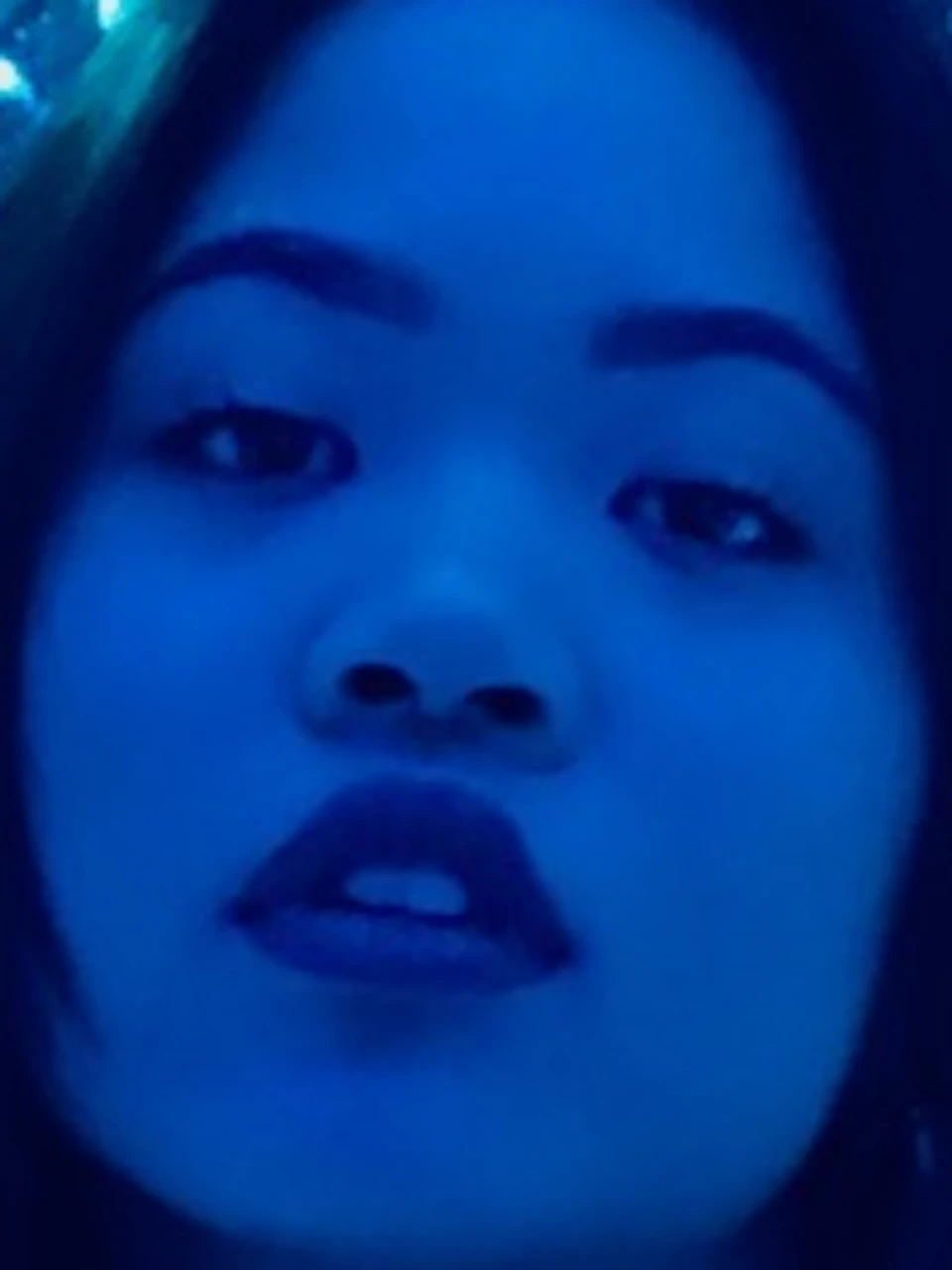 A woman stands in a room filled with blue LED lights and reflective surfaces, creating an immersive, sparkling backdrop.