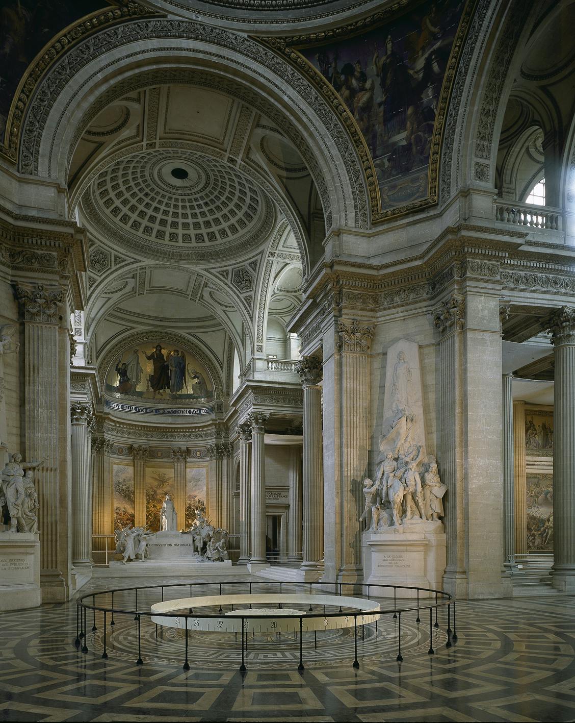 Grand interior of a neoclassical building with tall columns, statues, intricate dome ceiling, and large wall murals.
