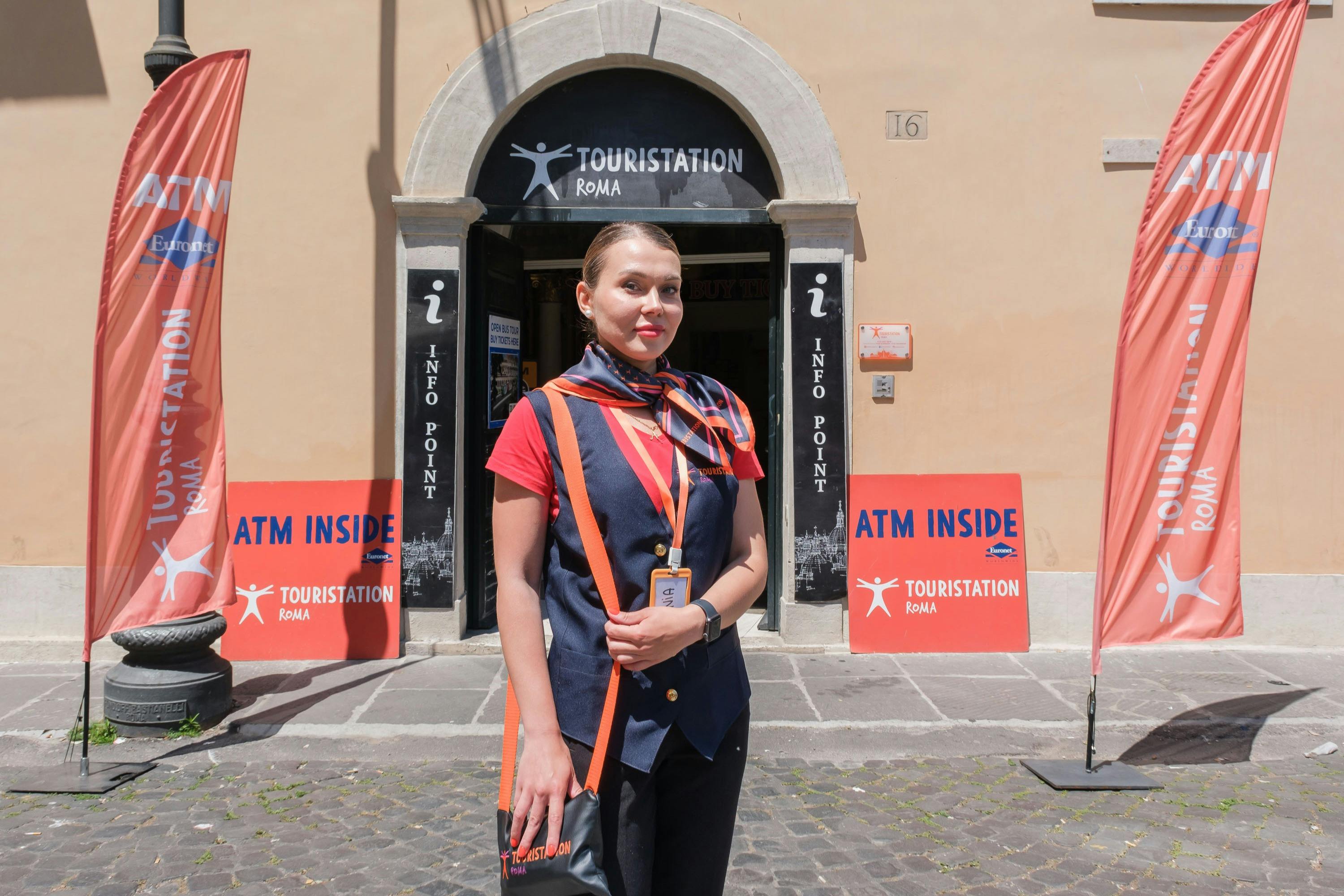 Una persona che indossa un'uniforme e una sciarpa si trova davanti a un centro di informazioni turistiche con l'insegna 