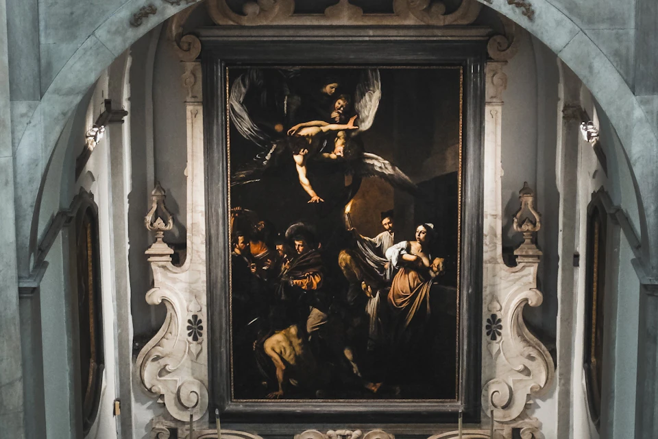 A painting in an ornate frame depicting a dramatic scene with multiple figures and dynamic lighting, displayed in a classical setting.