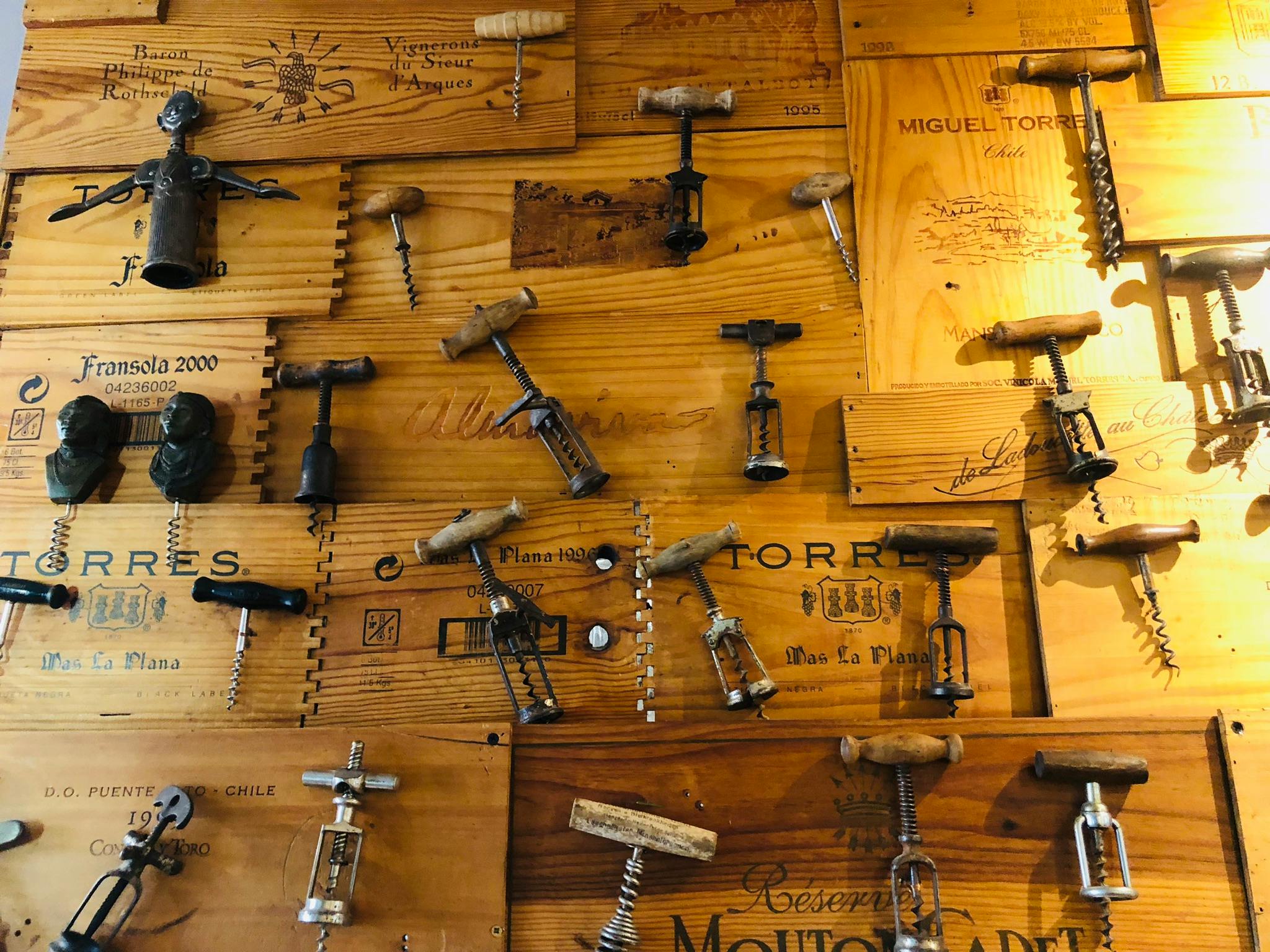 Ένας ξύλινος τοίχος εμφανίζει μια συλλογή από διάφορα τιρμπουσόν, διατεταγμένα σε ένα οργανωμένο μοτίβο.