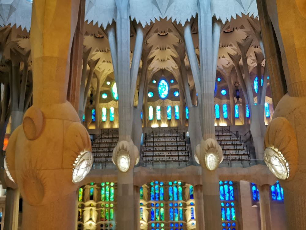 Interior of a cathedral with tall columns, intricate ceiling, and colorful stained glass windows.