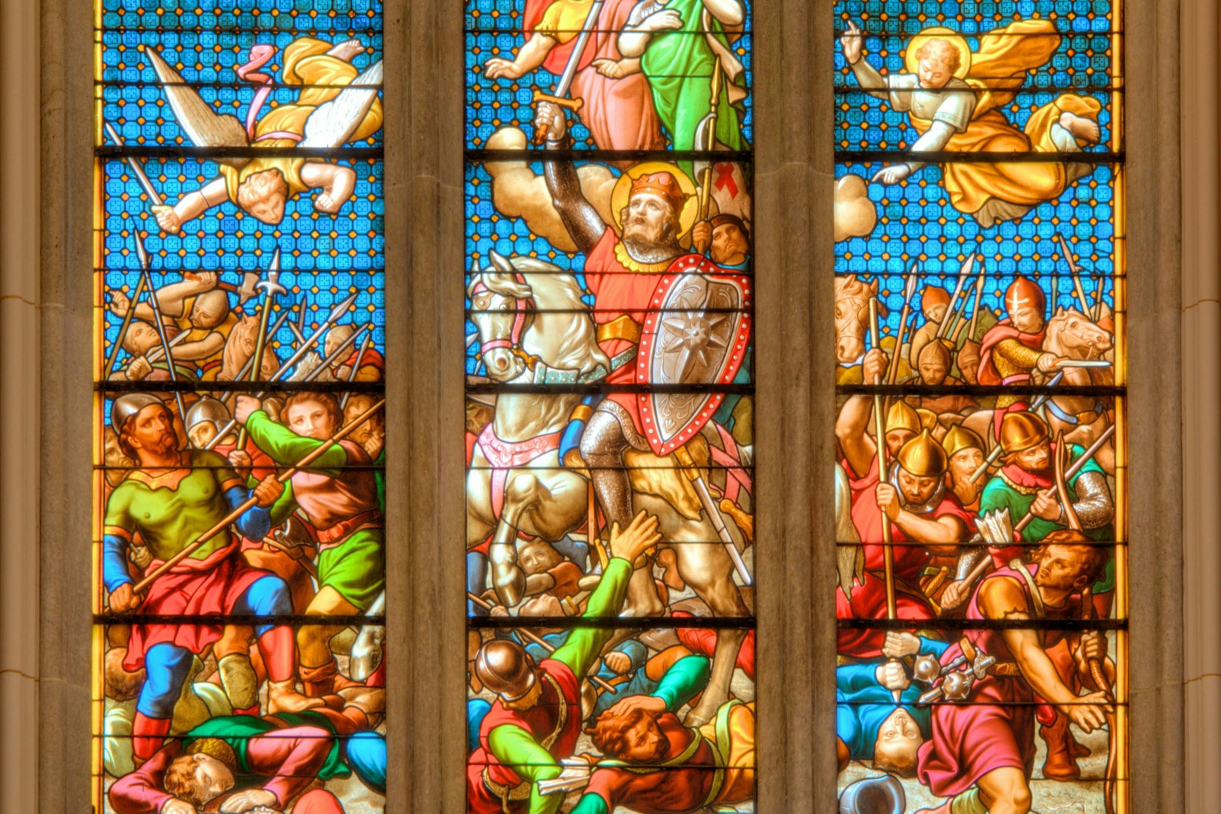 A stained glass window depicting a medieval battle scene with soldiers, a horse, and a knight holding a shield.