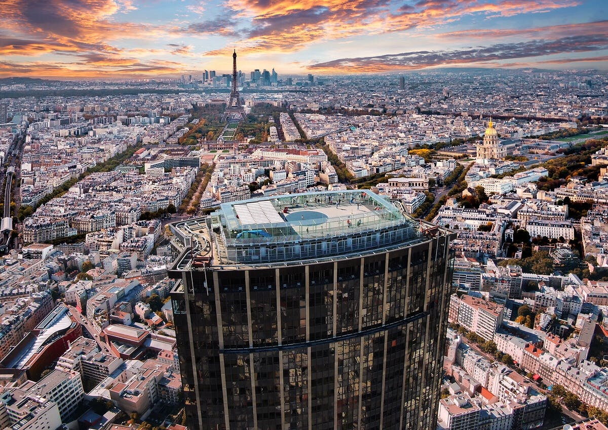 目立つ高層ビルが目の前にあり、人々が住む屋上エリアを眺めることができます。 鮮やかな夕日の下、背景にエッフェル塔が見えます。