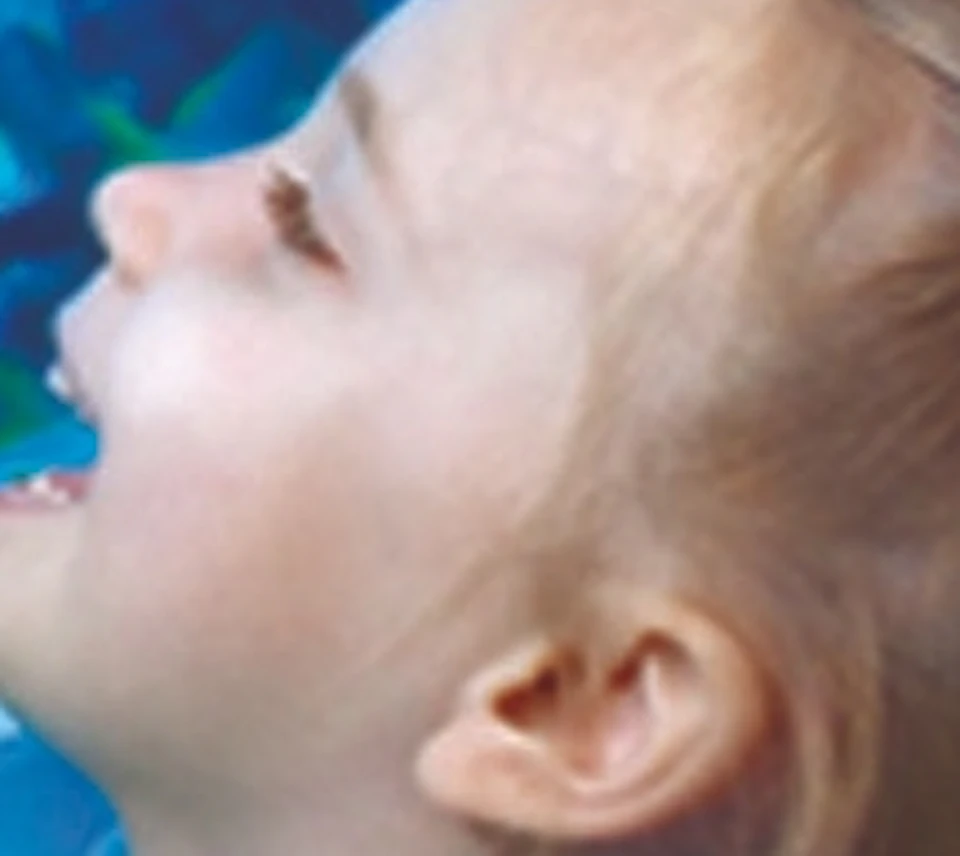 A child points excitedly at fish in an aquarium while a diver with a flashlight swims nearby. Bright blue water and colorful fish surround them.