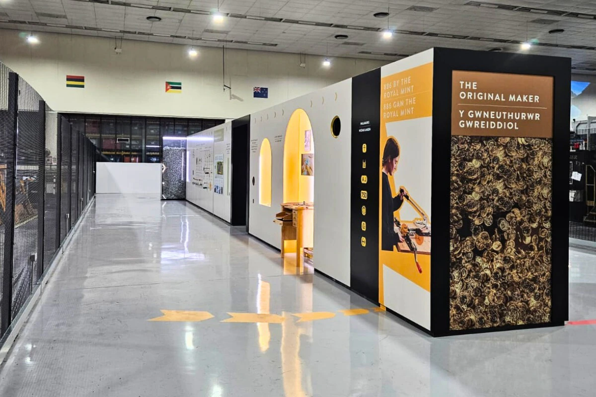 Indoor exhibition space with large black and white displays, including images and text about the Royal Mint. The floor is reflective.