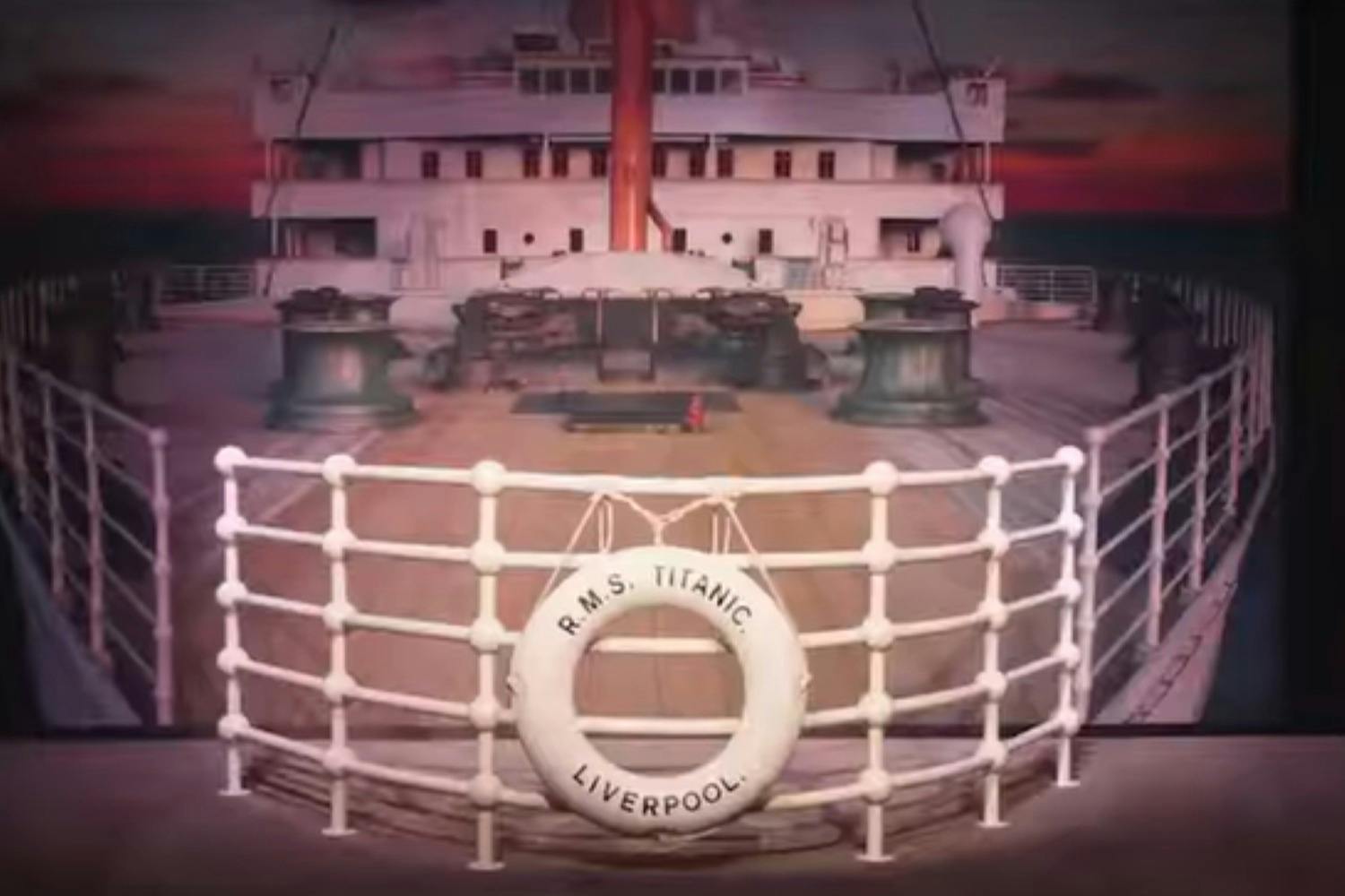 The deck of a ship labeled R.M.S. Titanic Liverpool, featuring railings and deck equipment, under a twilight sky.