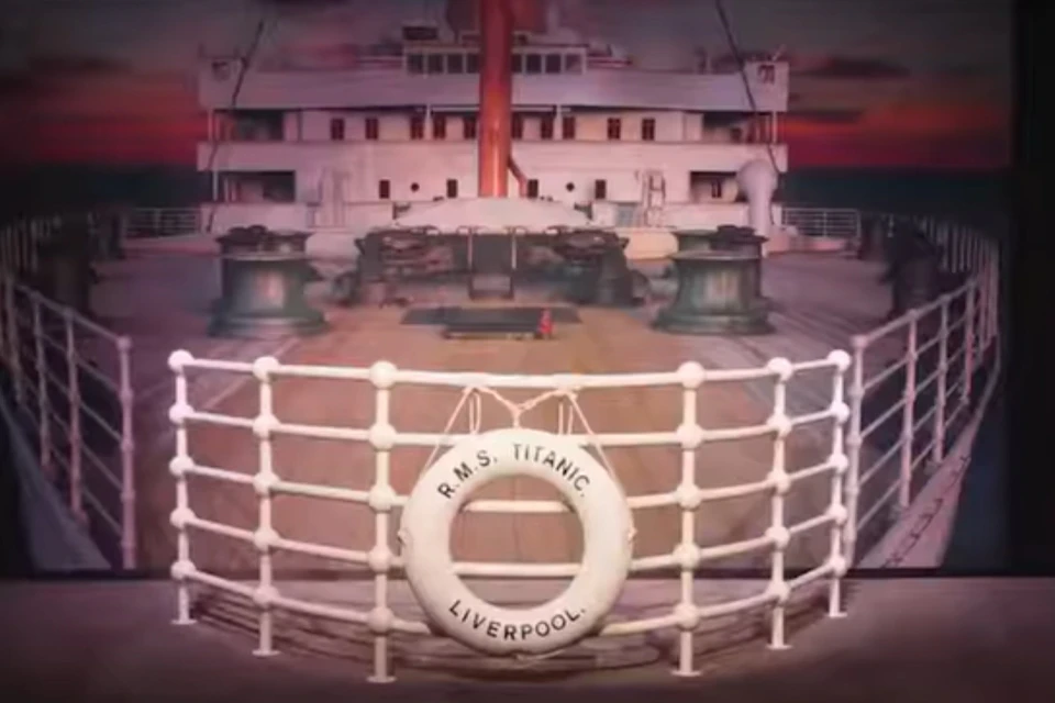 The deck of a ship labeled R.M.S. Titanic Liverpool, featuring railings and deck equipment, under a twilight sky.