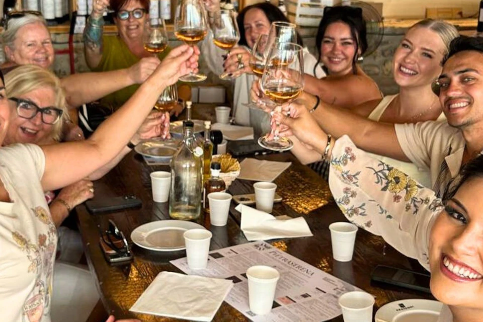 A group of people sitting at a table in a restaurant, raising glasses, smiling, and celebrating together.