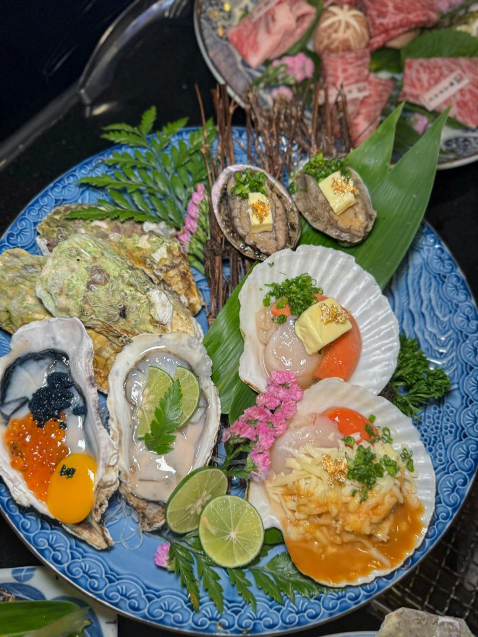 A plate of assorted fresh seafood, including oysters, scallops, and garnishes, served on a decorative blue platter.