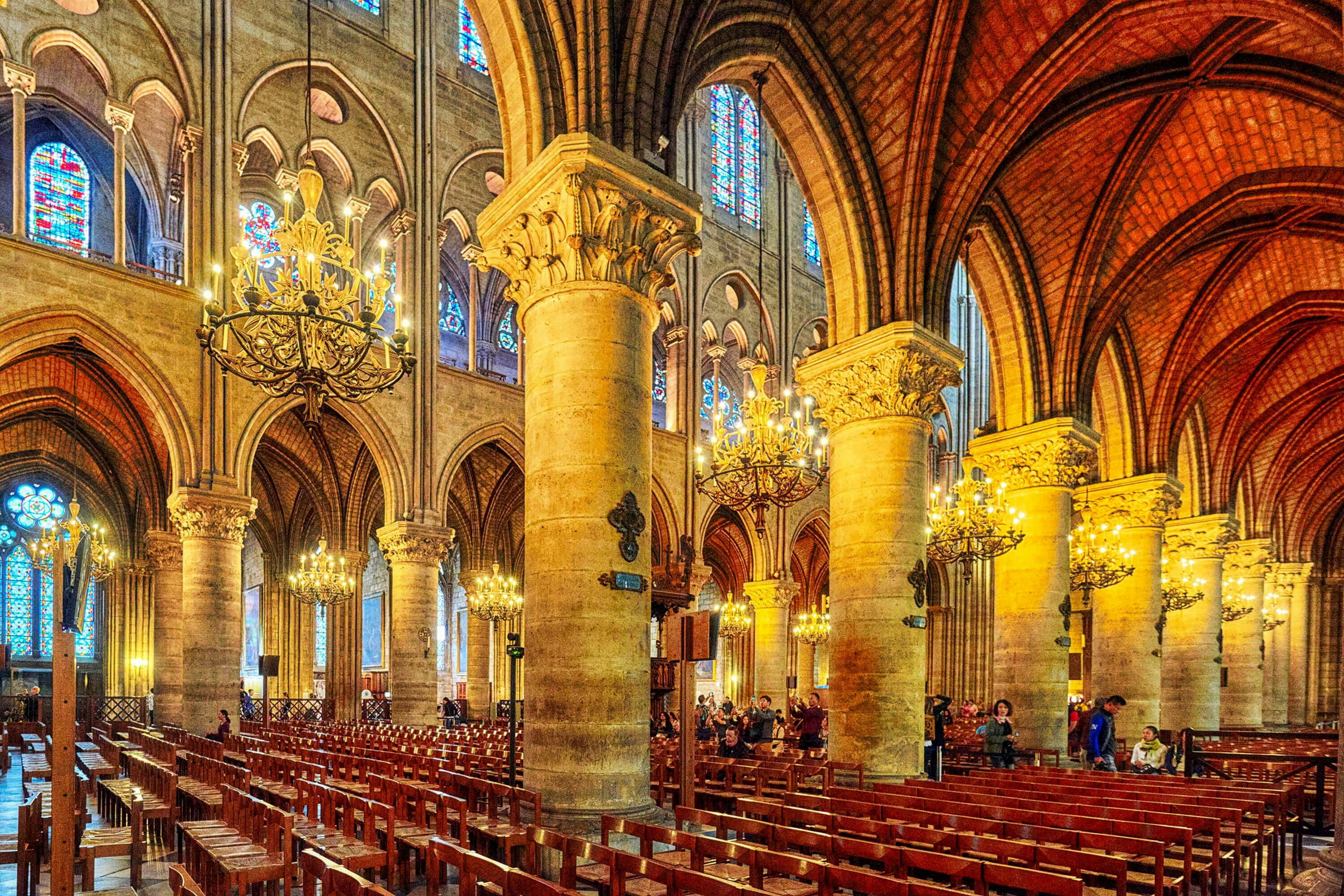 Εσωτερική άποψη ενός καθεδρικού ναού με ψηλούς πυλώνες, τοξωτές οροφές, πολυελαίους, βιτρό παράθυρα και ξύλινα στασίδια.