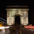 Long-exposure shot of the Arc de Triomphe at night with light trails from cars