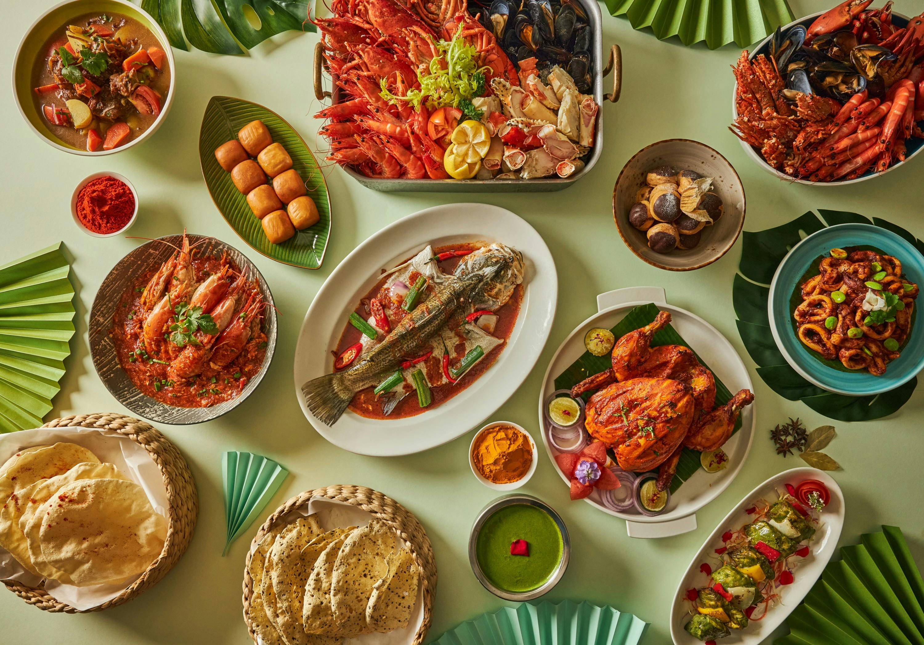 A variety of dishes including seafood, grilled chicken, and bread arranged on a table with a green background.