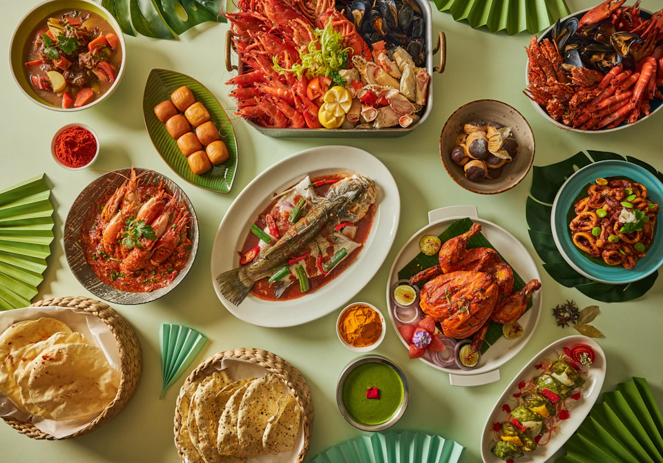 A variety of dishes including seafood, grilled chicken, and bread arranged on a table with a green background.