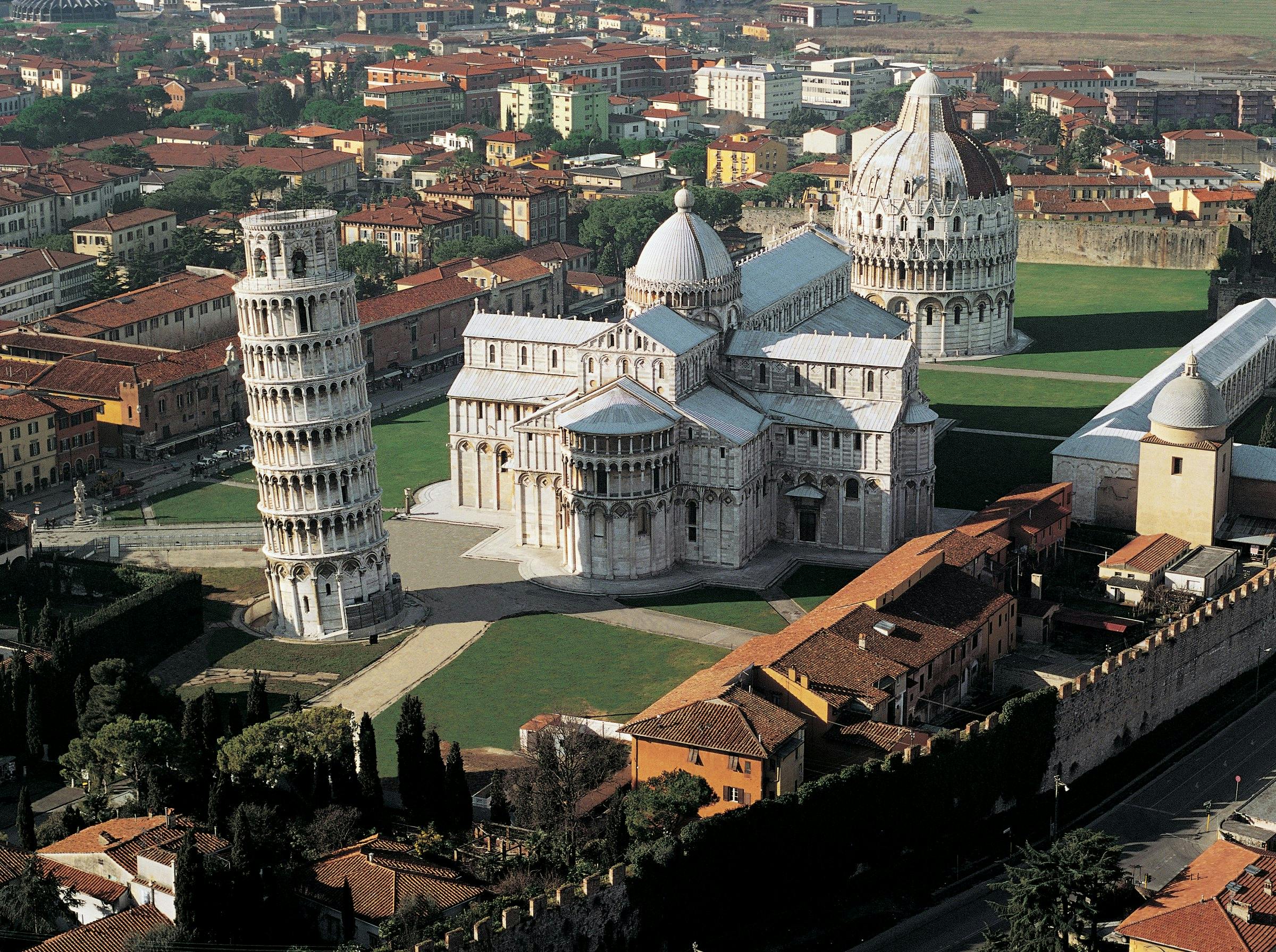 比萨斜塔（ Leaning Tower of Pisa ）、比萨大教堂（ Pisa Cathedral ）和洗礼堂（ Baptistery ）的鸟瞰图，周围环绕着建筑和绿色植物。