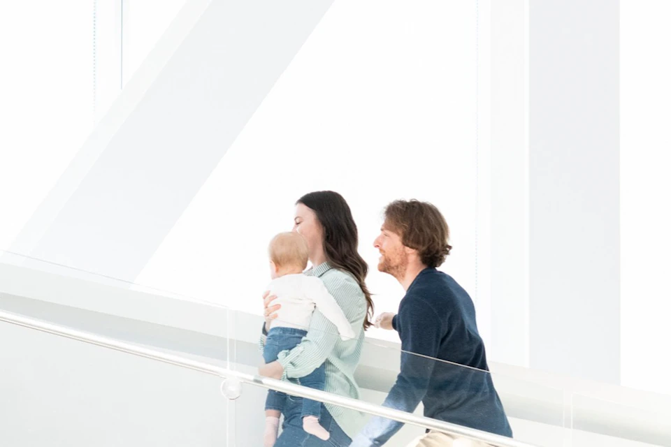 People walking up and down a modern staircase with glass railings and bright lighting.
