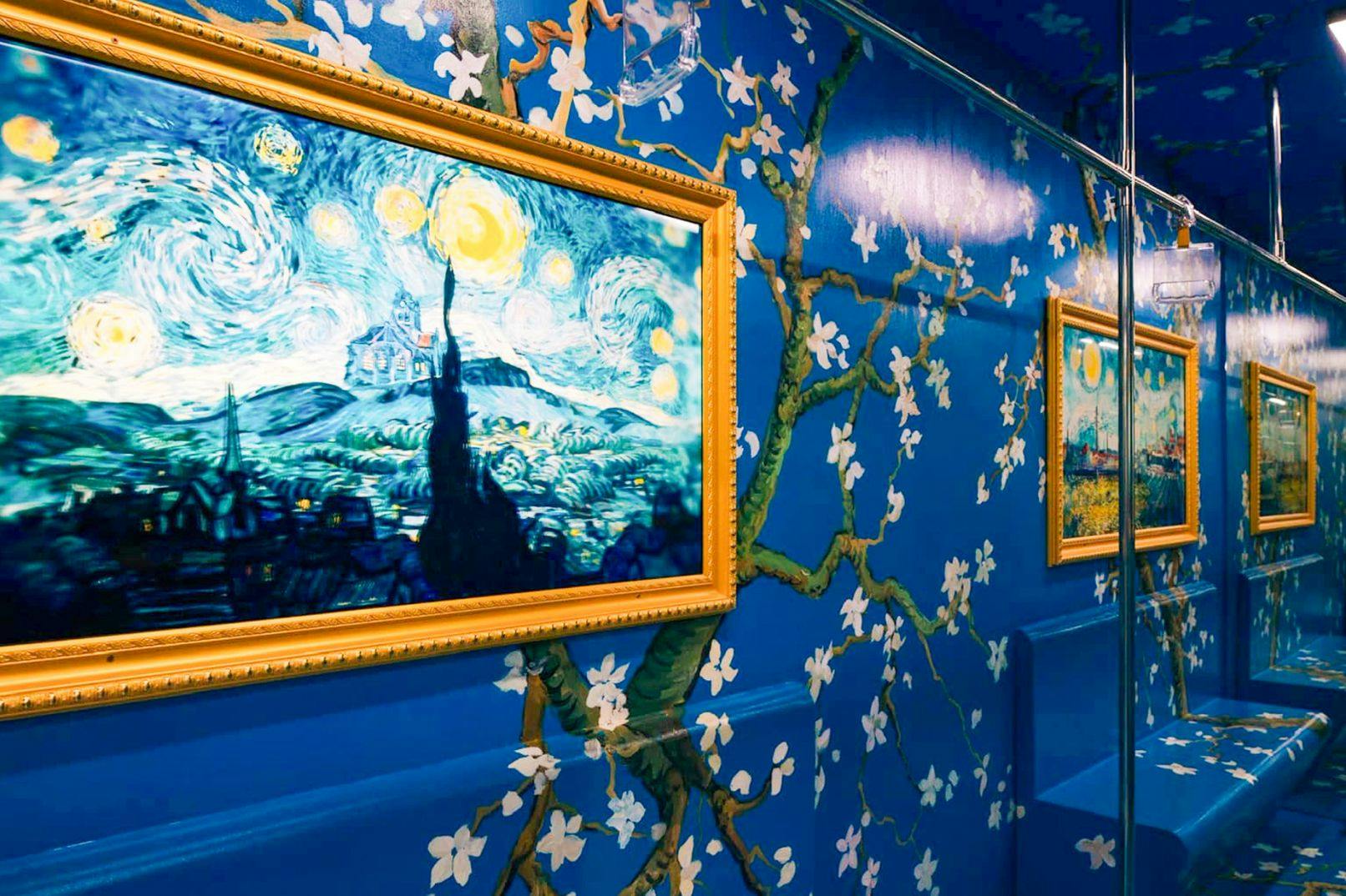 Uma divisão cheia de vida, com uma parede com um padrão floral azul, decorada com quadros emoldurados de Van Gogh e superfícies refletoras.