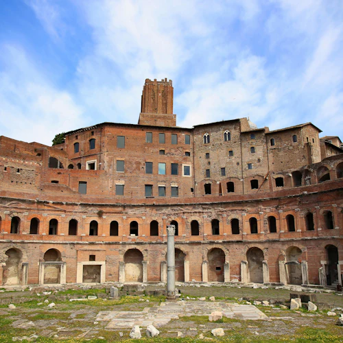 Forntida romerska tegelruiner med välvda fönster, en pelare i mitten och en klarblå himmel ovanför.
