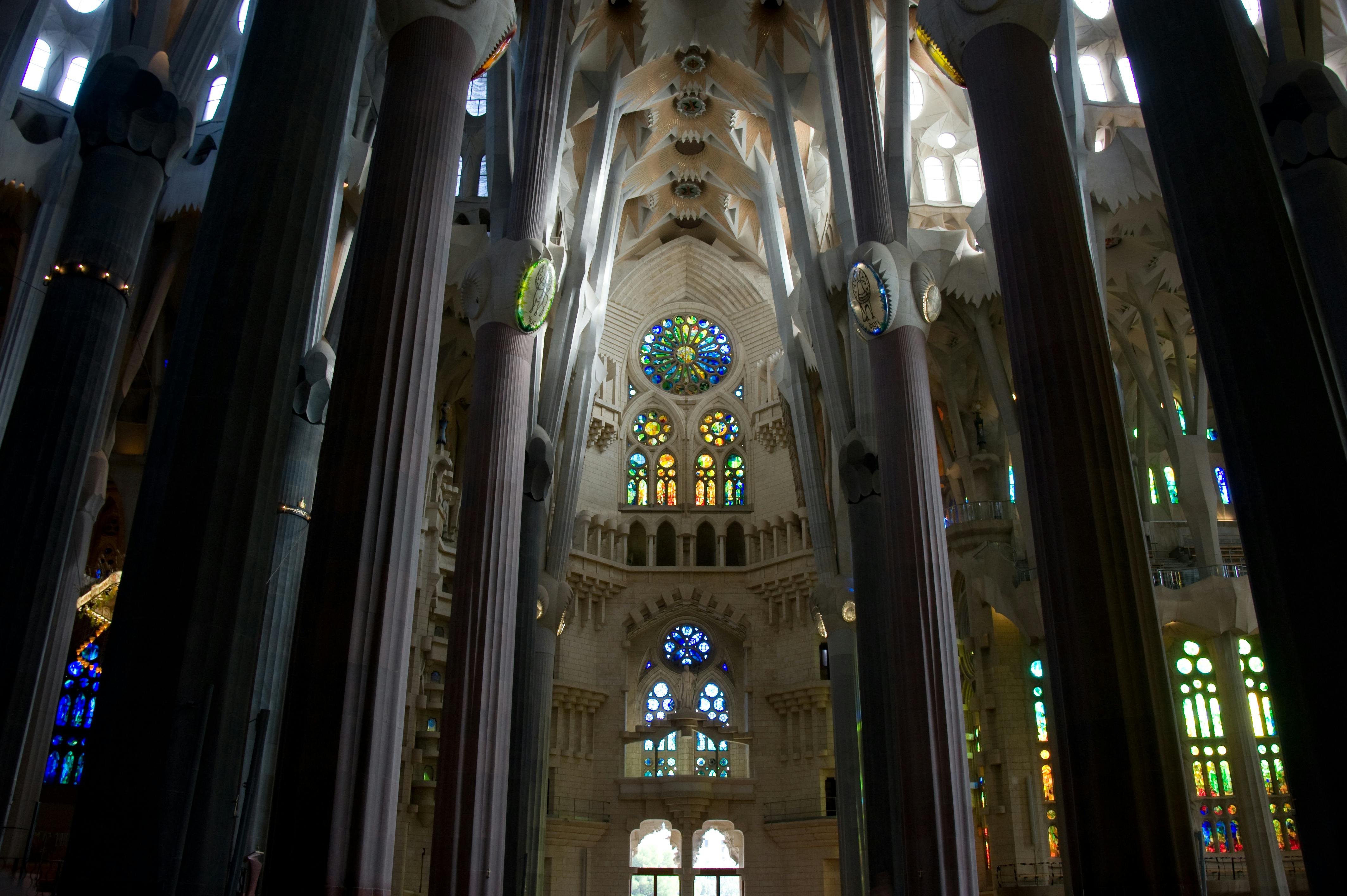 Interior of a grand cathedral with tall columns, ornate stained glass windows, and a detailed, vaulted ceiling.